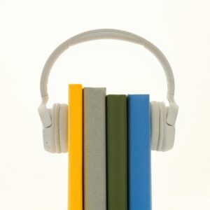 White headphones resting on colorful books, symbolizing modern audio technology.