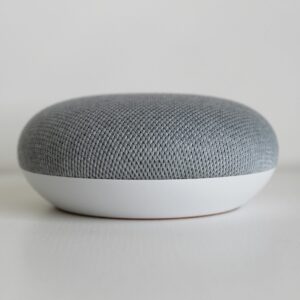 A close-up shot of a round, minimalist smart speaker on a white surface, highlighting modern design.