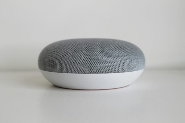 A close-up shot of a round, minimalist smart speaker on a white surface, highlighting modern design.