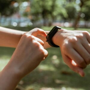 A person interacts with a smartwatch in a sunny park, emphasizing fitness and technology.